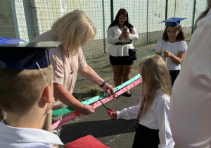 Uczennica przecina wstęgę.