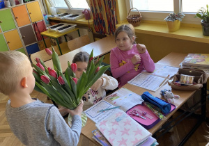 Chłopcy rozdają tulipany dziewczynkom.