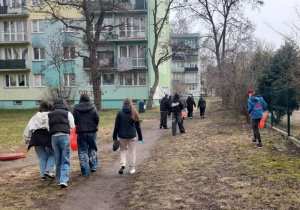 Zdjęcie, na którym grupa młodzieży sprząta teren w pobliżu szkoły.